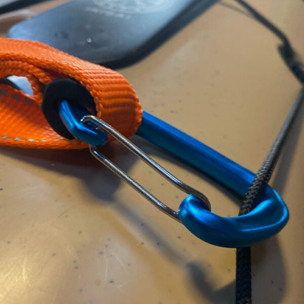 designkayaks Segla Gear Quick Release Contact Tow til havkajak eller kort trækline til havkajak er perfekt til kontaktbugsering og redninger her vist fastgjort til fordæk med anodiserede aluminiumskarabiner og synlig reflekterende syning på den orange weebing