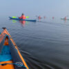 designkayaks social paddling club - et hold roere på vej gennem blikstille vand på en let diset solskinsmorgen