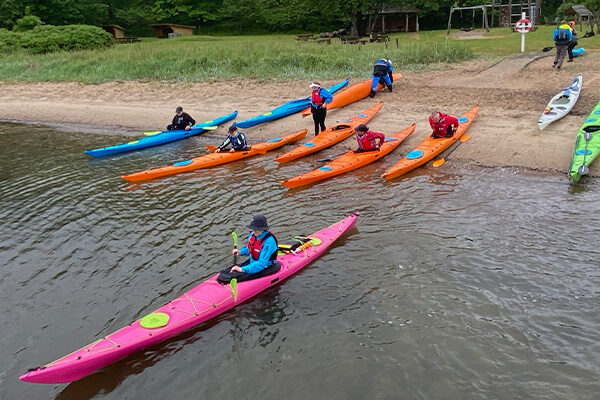 designkayaks social paddling club - et hold roere sætter i vandet fra stranden